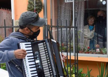 Un chileno toca el acordeón frente a la ventana de sus padres para animarlos en la cuarentena por el coronavirus